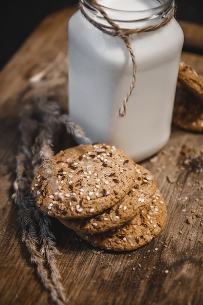 Galletas de cereales con una jarra de leche sobre un fondo de madera.