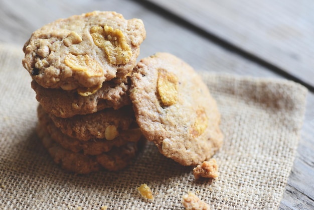 Galletas con chispas de chocolate en el fondo de la tabla de saco, cerca de los copos de maíz de la galleta