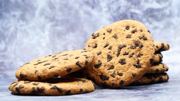 Galletas con chispas de chocolate suaves y recién horneadas en una encimera de cocina de mármol gris. Pastelería dulce tradicional americana, delicioso postre casero. Fondo culinario.