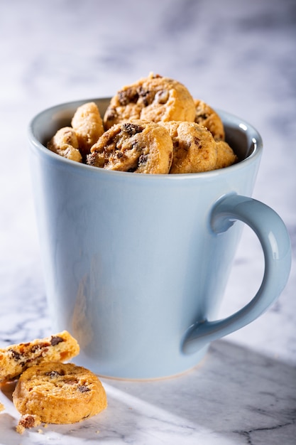 Galletas con chispas de chocolate en taza azul sobre la superficie de piedra de mármol. Enfoque selectivo. Copia espacio