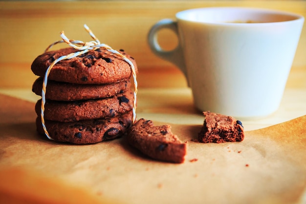 galletas con chispas de chocolate y taza de café sobre fondo de madera