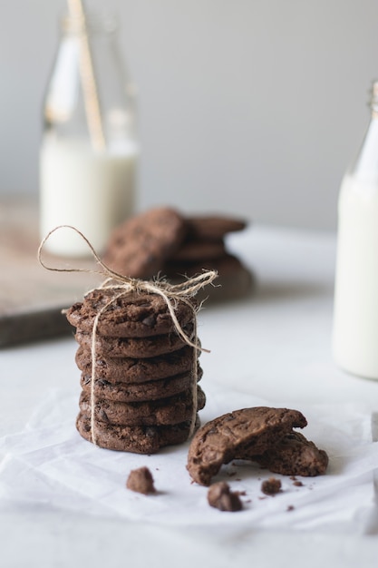 Galletas de chocolate con botellas de leche sobre un papel rústico