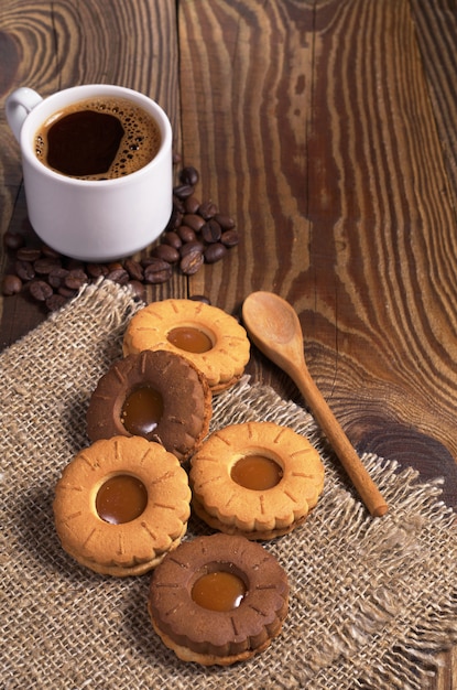 Galletas de chocolate con caramelo y una taza de café en la mesa de madera vieja