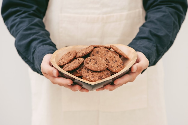 Galletas de chocolate caseras en placa en manos masculinas.