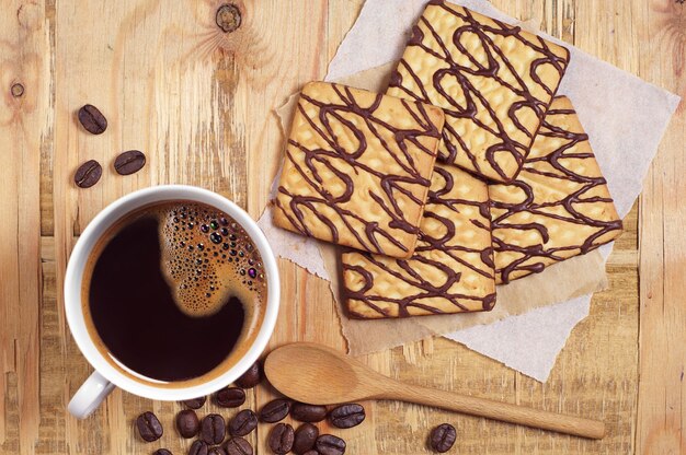 Galletas de chocolate dulce con taza de café para el desayuno en la vieja mesa desde arriba