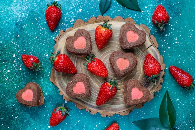 Galletas de chocolate y fresa en forma de corazón con fresas frescas, vista superior