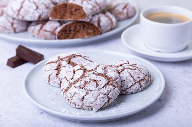 Galletas de chocolate con grietas, untadas con azúcar glas y una taza de café.