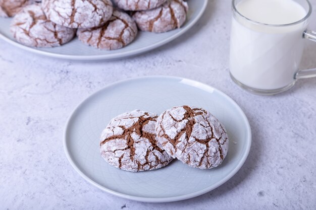 Galletas de chocolate con grietas, untadas con azúcar glas y una taza de leche