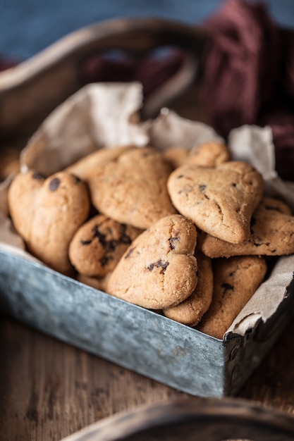 Galletas de chocolate en la mesa rústica de madera. Galletas de chispas de chocolate en forma de corazón. Galletas caseras