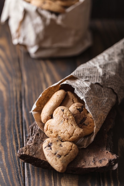 Galletas de chocolate en la mesa rústica de madera. Galletas de chispas de chocolate en forma de corazón. Galletas caseras