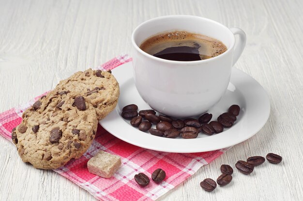 Galletas con chocolate y taza de café en una mesa de madera clara