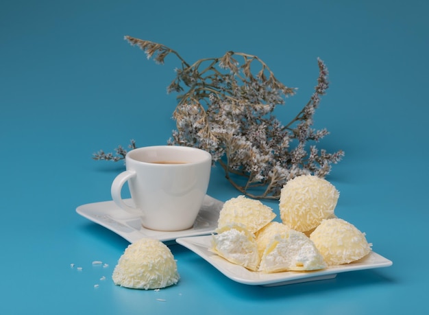 galletas de coco en un plato blanco de fondo azul con una taza de café