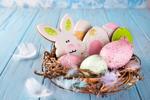 Galletas coloridas de pascua del final del huevo de Pascua como conejo y huevo en la jerarquía en el fondo de madera