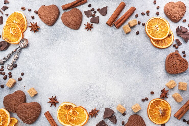 Galletas de corazón de chocolate, naranjas, canela y especias picantes en una mesa gris, vista superior, espacio de copia.