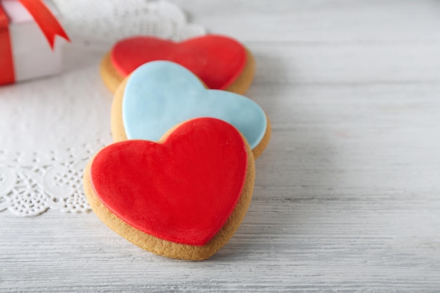 Galletas de corazón de San Valentín con caja presente sobre fondo de madera