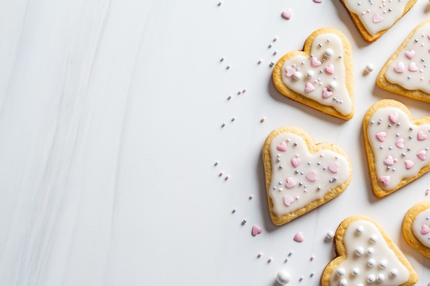 Galletas de corazones con glaseado y decoradas para el día de San Valentín, fondo blanco, espacio de copia.