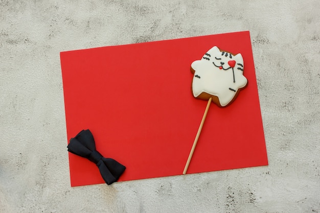 Galletas decoradas con forma de corazón y pajarita en hoja roja