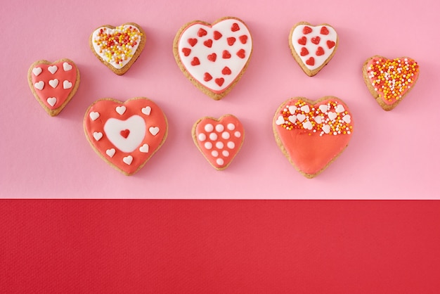 Galletas decoradas en forma de corazón sobre fondo rosa