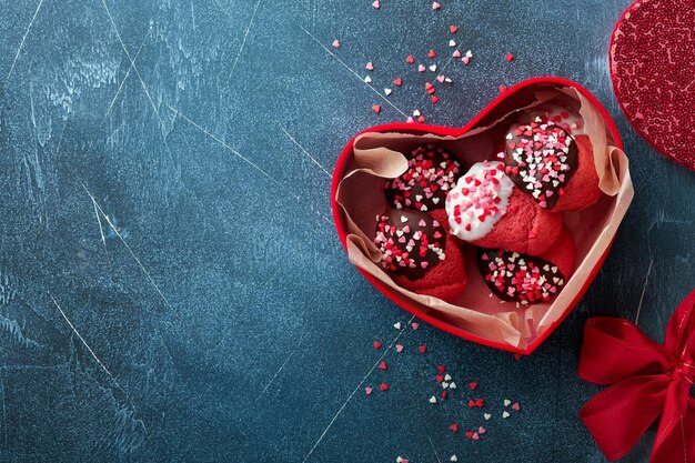 Galletas del día de San Valentín Galletas de mantequilla con glaseado de chocolate blanco y negro y chispas de corazón en una caja roja sobre fondo azul oscuro Día de la madre Día de la mujer Dulces vacaciones para hornear Vista superior