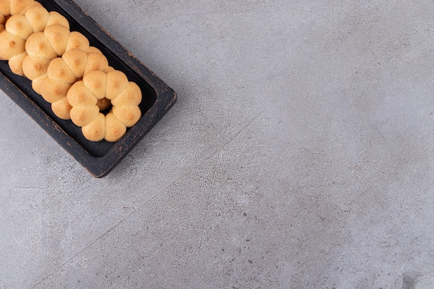 Galletas dulces en forma de flor en una tabla de madera oscura.