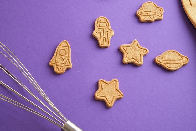 Galletas estrellas y astronauta para el día mundial de la cosmonáutica galletas sobre fondo púrpura Concepto de espacio y astronomía