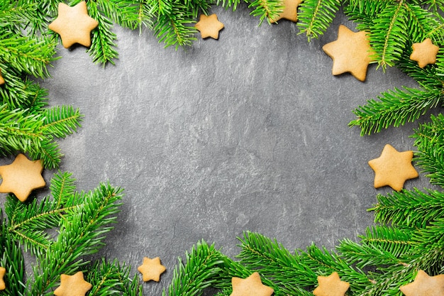 Galletas de estrellas de pan de jengibre tradicionales de Navidad con ramas de árboles de Navidad sobre un fondo de piedra oscura Vista superior Espacio de copia