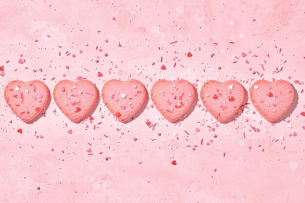 Galletas en forma de corazón decoradas sobre fondo rosa