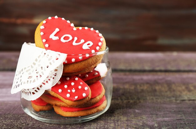 Galletas en forma de corazón para el día de san valentín en frasco de vidrio sobre fondo de madera de color