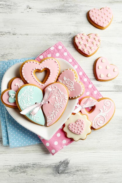 Galletas en forma de corazón para el día de san valentín en un plato, sobre fondo de madera de color