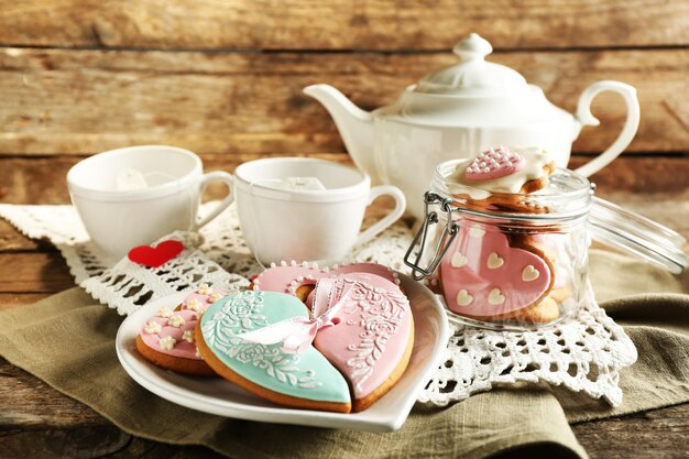 Galletas en forma de corazón para el día de san valentín y tetera sobre fondo de madera