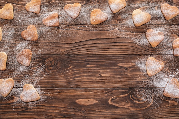 Galletas en forma de corazón espolvoreado con azúcar en polvo sobre una mesa de madera