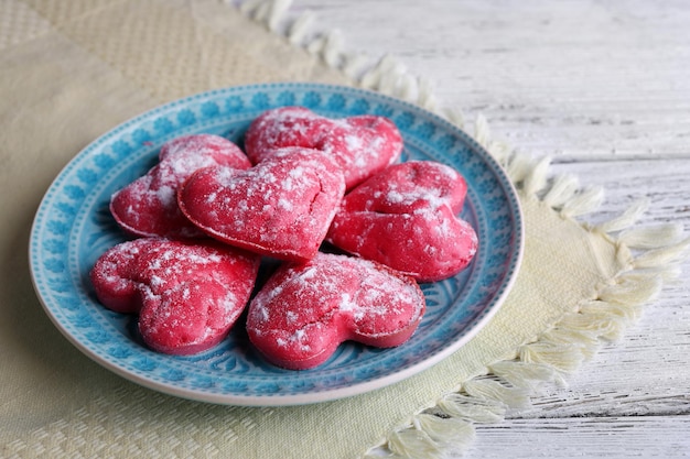 Galletas en forma de corazón en placa sobre fondo de mesa de madera de color