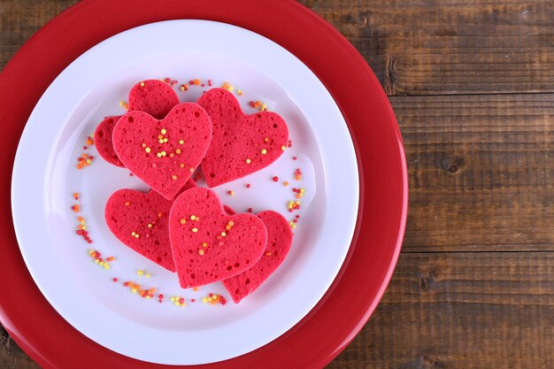 Galletas en forma de corazón en plato sobre fondo rústico de tablones de madera