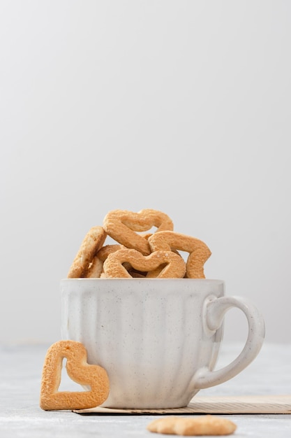 Galletas en forma de corazón en una taza blanca Fondo claro