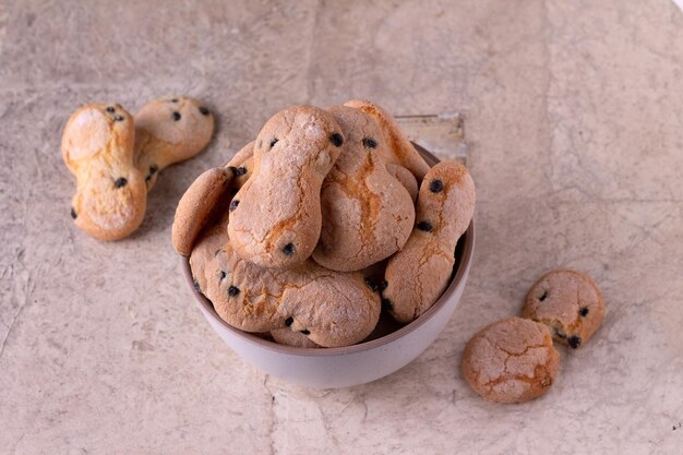 Galletas en forma de ochos con arándanos en un plato redondo sobre un fondo de textura beige