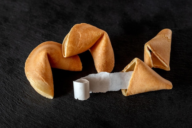 Galletas de la fortuna con papel enrollado en blanco sobre fondo oscuro