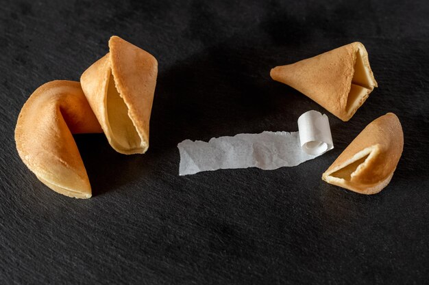 Galletas de la fortuna con papel enrollado en blanco sobre fondo oscuro