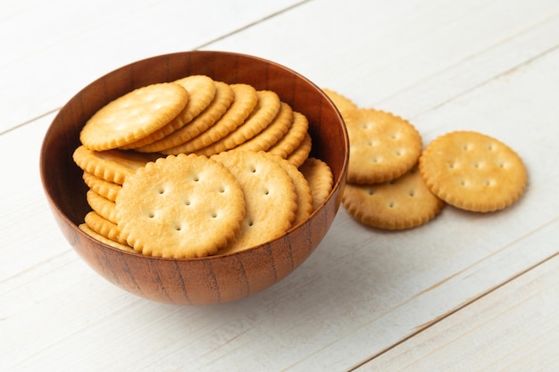 Galletas de galleta redondeadas en un cuenco de madera sobre fondo de mesa de madera blanca.