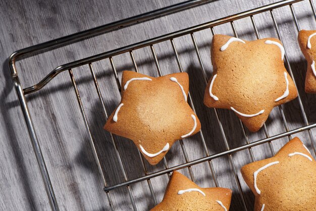 Galletas de ginder en forma de estrella recién horneadas en rejilla de enfriamiento. Primer plano, vista superior.