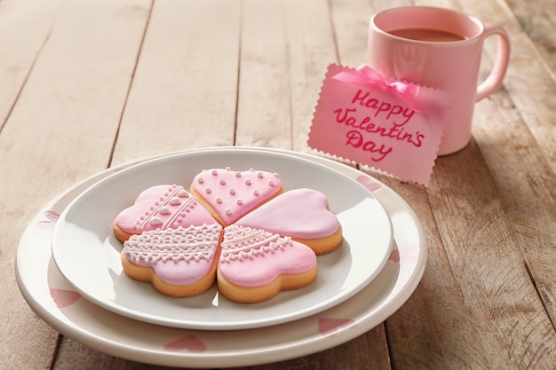 Galletas glaseadas en forma de corazón y tarjeta de San Valentín sobre fondo de madera