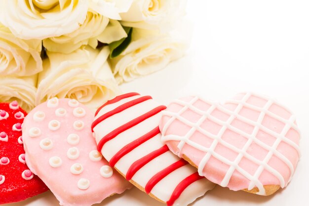 Galletas gourmet con ramo de rosas blancas.