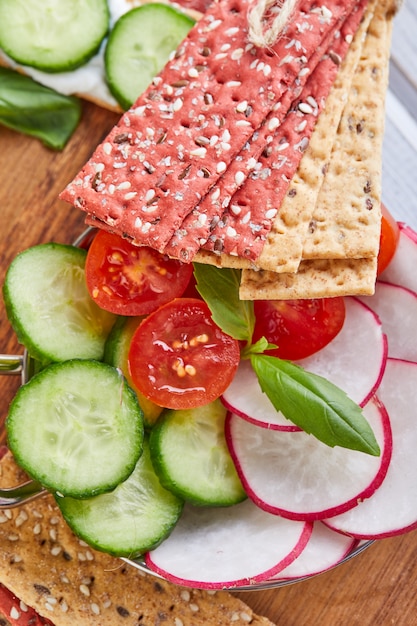 Galletas de harina de remolacha y centeno con verduras para hacer bocadillos en una mesa de madera. Vegetarianismo y alimentación saludable