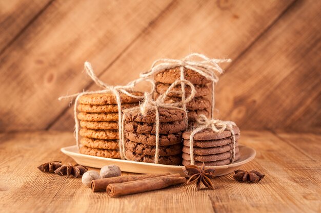 Galletas integrales con cable caseras con avena, lino y semillas de sésamo y galletas tradicionales con chispas de chocolate en la mesa de madera rústica oscura y especias.