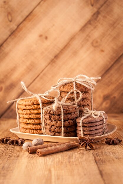 Galletas integrales con cable caseras con avena, lino y semillas de sésamo y galletas tradicionales con chispas de chocolate en la mesa de madera rústica oscura y especias.