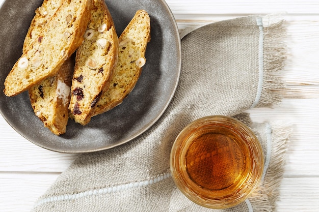 Galletas italianas de biscotti en plato gris y vino dulce Vin Santo Galletas frescas horneadas con nueces