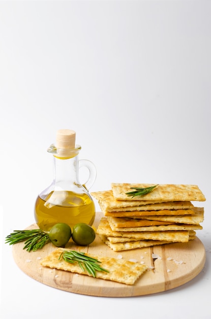 Galletas italianas con romero, aceitunas y aceite de oliva sobre tabla de madera