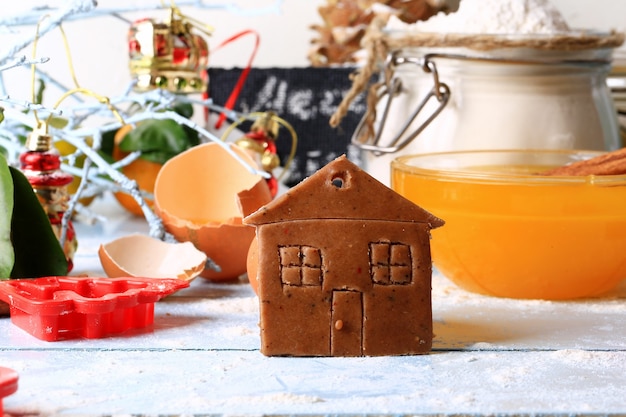 Foto galletas de jengibre casa pequeña pasteles caseros de navidad sobre un fondo de madera clara enfoque suave selectivo estilo rústico