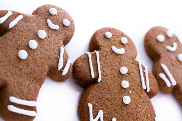 Galletas de jengibre caseras decoradas con glaseado blanco sobre fondo blanco.