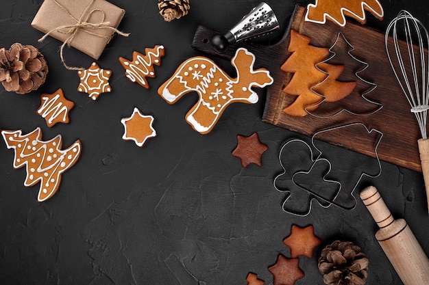 Galletas de jengibre caseras de Navidad, especias y tabla de cortar sobre fondo oscuro con espacio de copia para la vista superior del texto. Concepto de vacaciones, celebración y cocina. Postal de navidad y año nuevo