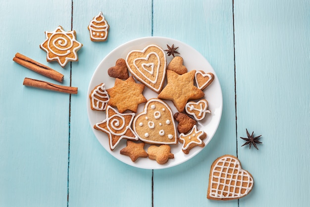 Galletas de jengibre decoradas con glaseado en un plato sobre un fondo de madera azul